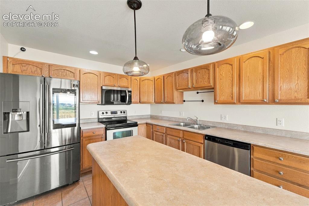 Image 18 of 50: Kitchen featuring medium-tone wood cabinetry, stainless steel appliances, s
