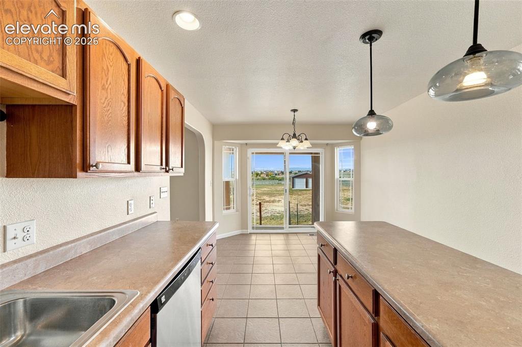 Image 20 of 50: Kitchen featuring wood cabinetry, solid-surface countertops, tile flooring,
