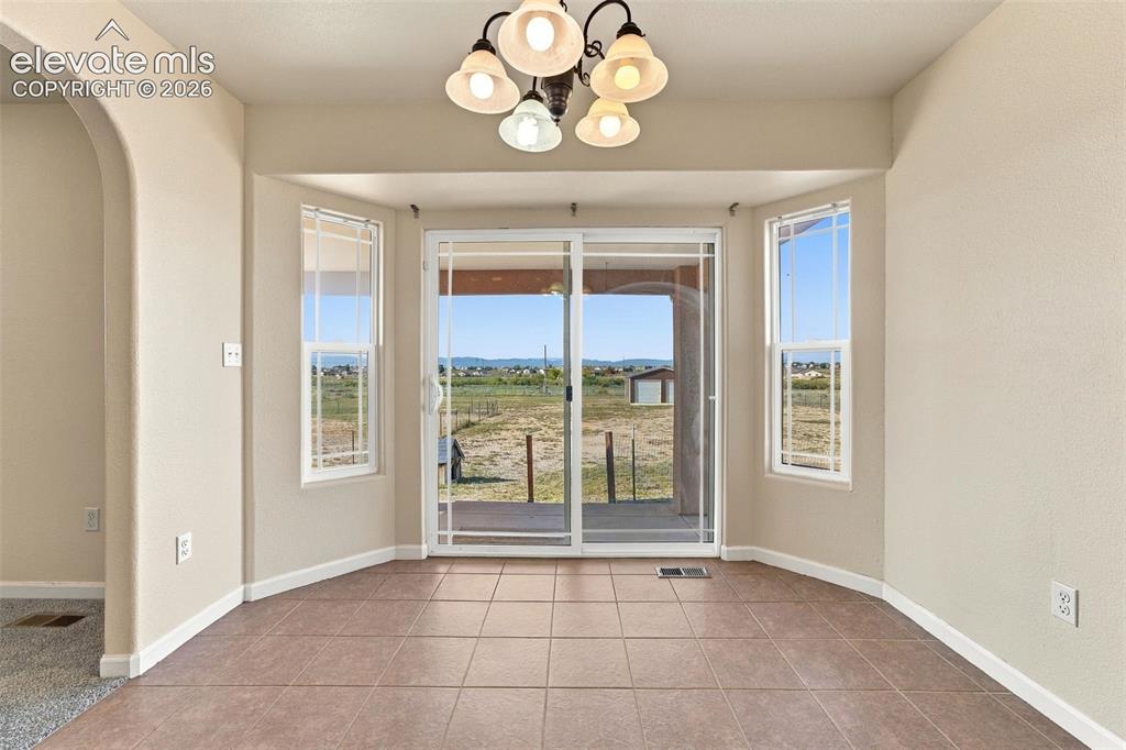 Image 22 of 50: Bay area featuring ceramic tile flooring, five-light chandelier, sliding gl