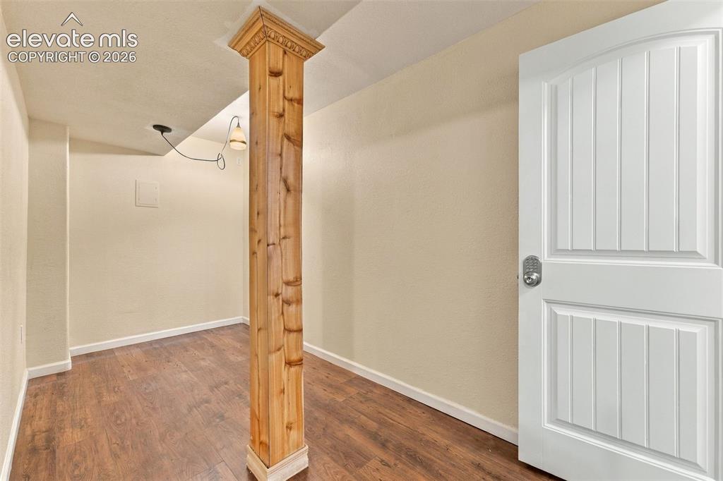 Image 23 of 50: Structural wood-finish post with crown molding detail, wood-finish flooring