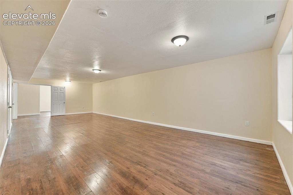 Image 24 of 50: Spacious interior featuring wood-finish flooring, neutral wall paint, and m