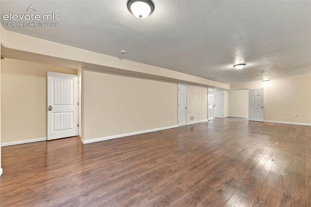 Image 25 of 50: Spacious interior featuring wood-finish flooring, neutral wall paint, multi