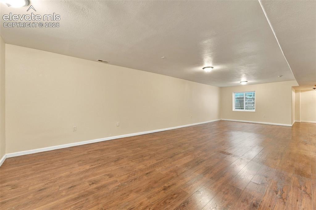 Image 27 of 50: Expansive interior space featuring wood-finish flooring, neutral wall paint