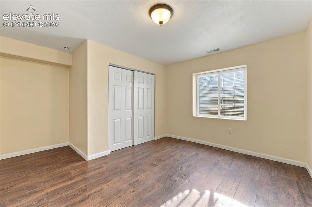Image 28 of 50: Wood-finish flooring, dual-panel sliding closet doors, and a double-pane wi