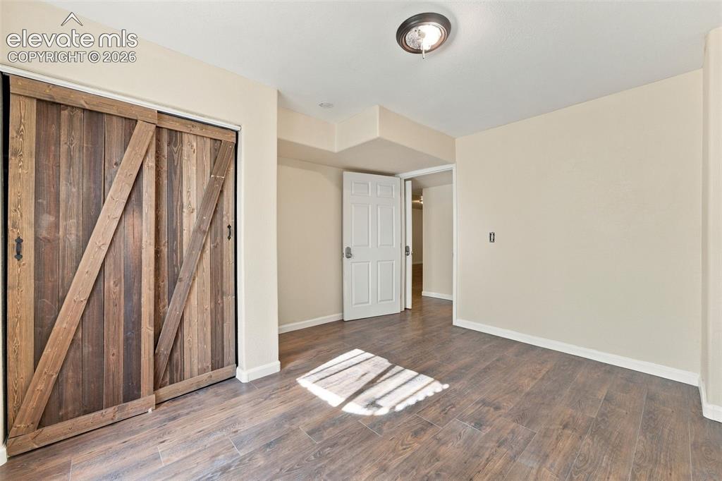 Image 31 of 50: Room featuring wood-finish flooring, sliding barn-style door with rustic ha
