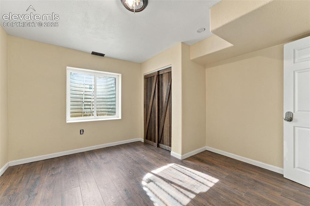 Image 32 of 50: Room featuring wood-finish flooring, sliding barn-style closet doors, and a
