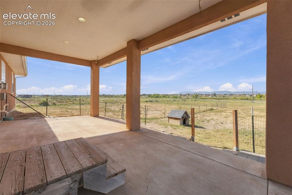 Image 34 of 50: Covered concrete patio featuring recessed lighting, support columns, and an