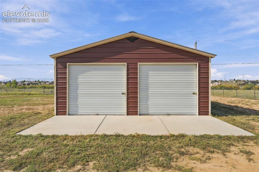 Image 35 of 50: Detached structure featuring metal siding, a gabled roof, two roll-up doors