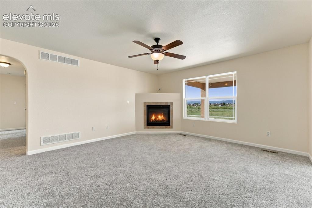 Image 4 of 50: Living area featuring a corner fireplace with stone surround, neutral wall-