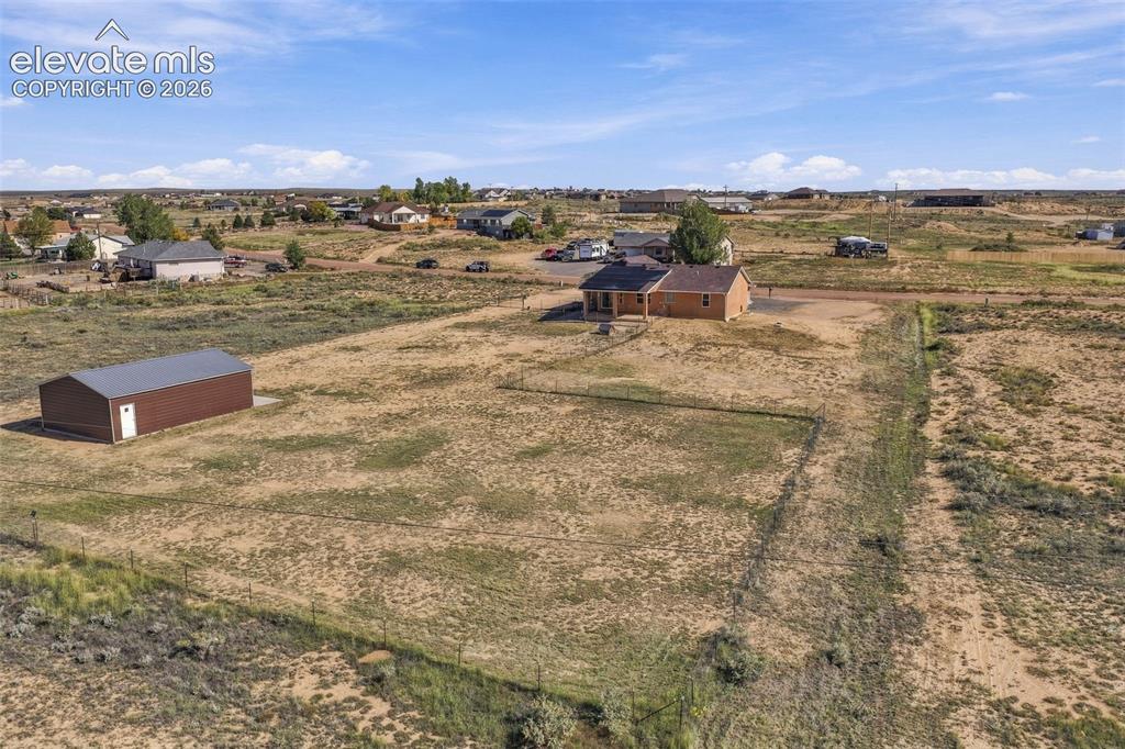 Image 44 of 50: Aerial perspective featuring a detached metal structure, fenced perimeter,