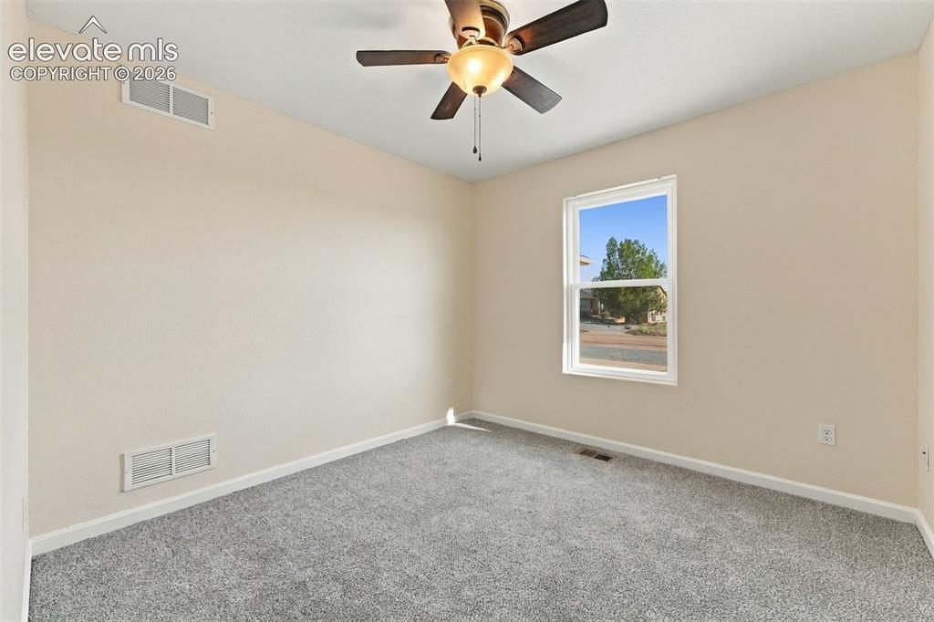 Image 7 of 50: Neutral wall color, grey carpeting, and a ceiling-mounted light fixture wit