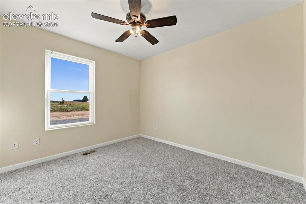 Image 9 of 50: Neutral-toned walls, high-pile carpeting, and a ceiling fan with integrated