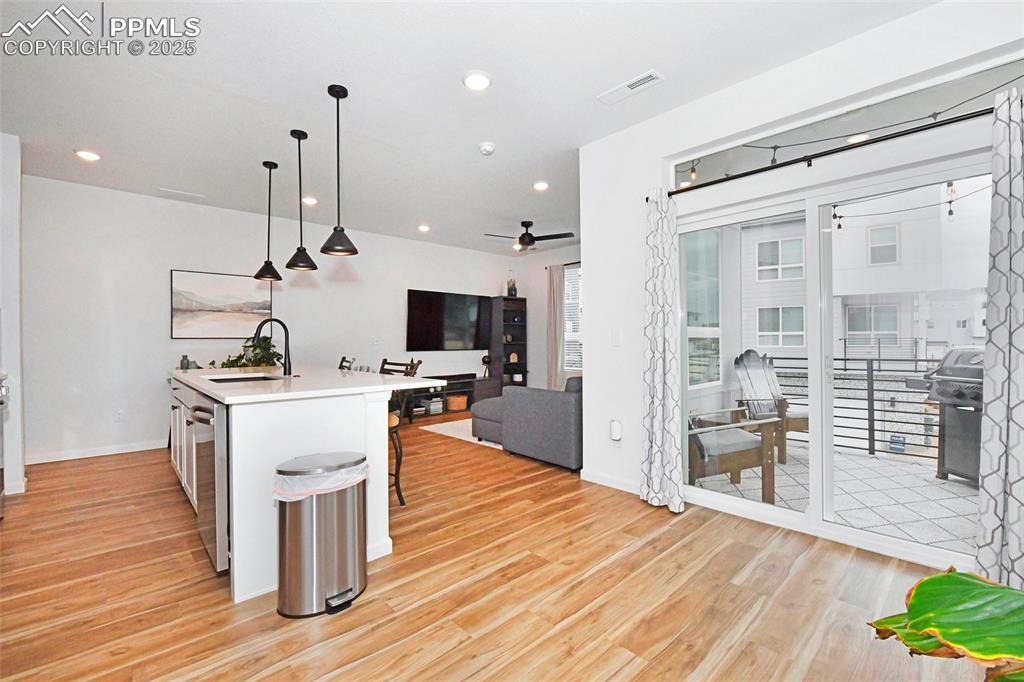 Image 11 of 26: Kitchen featuring hanging light fixtures, an island with sink, open floor p