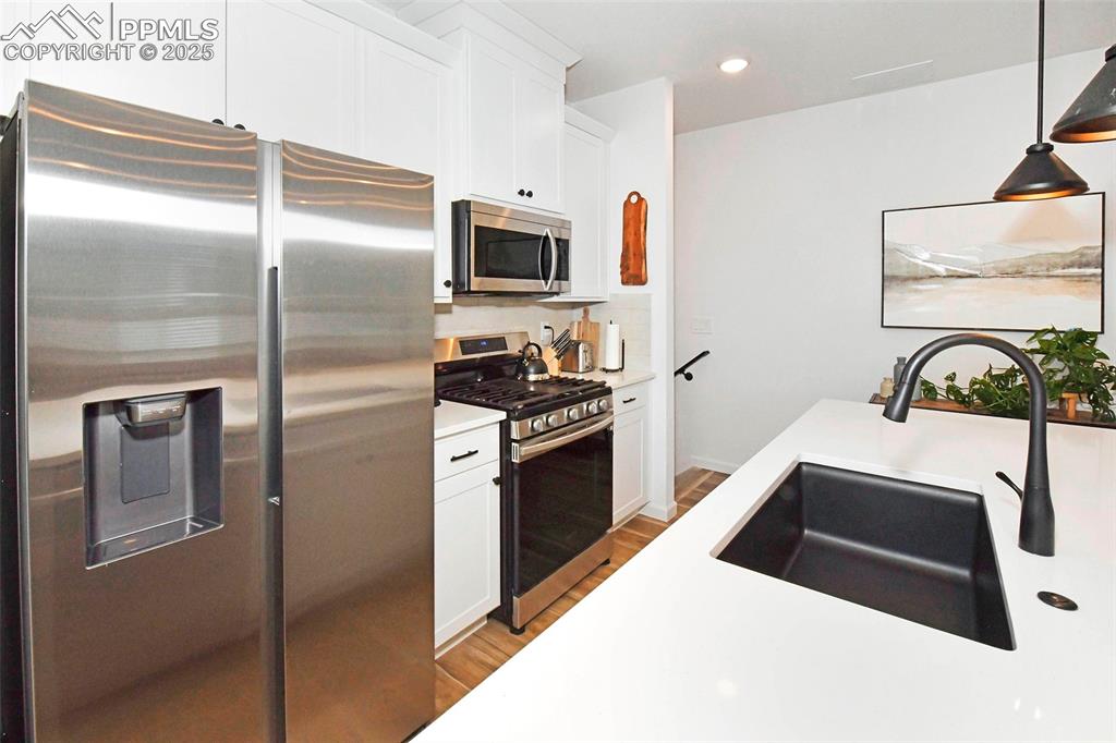 Image 12 of 26: Kitchen with stainless steel appliances, white cabinets, recessed lighting,