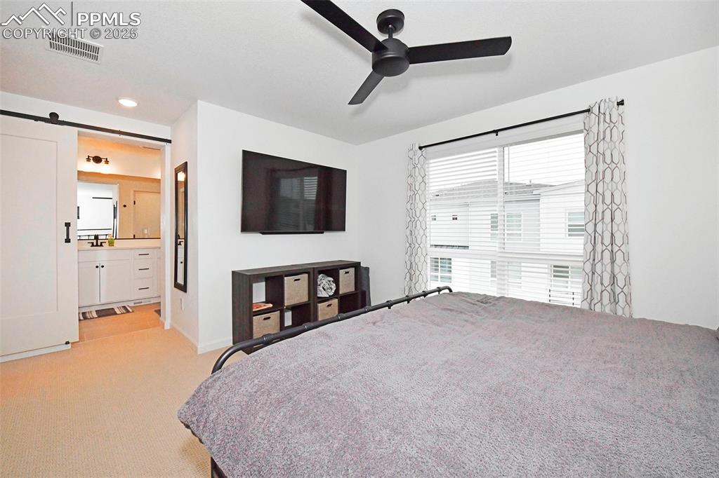 Image 18 of 26: Bedroom featuring a barn door, light carpet, a ceiling fan, recessed lighti