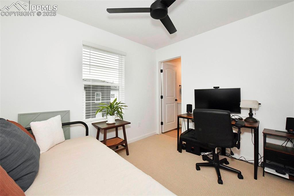 Image 21 of 26: Bedroom with an office area, light colored carpet, and ceiling fan