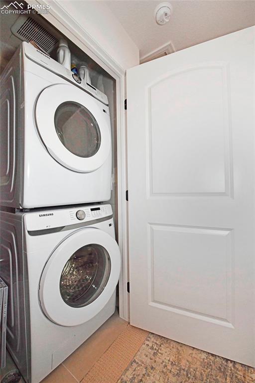 Image 23 of 26: Laundry room featuring stacked washing machine and dryer