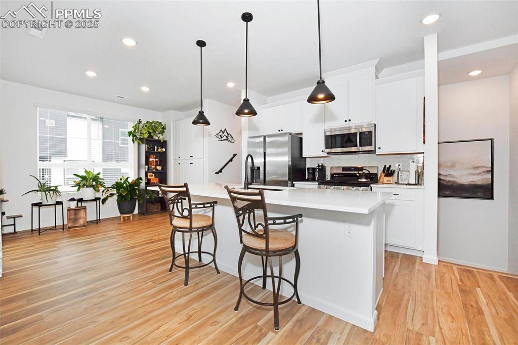 Image 9 of 26: Kitchen with white cabinets, stainless steel appliances, decorative light f
