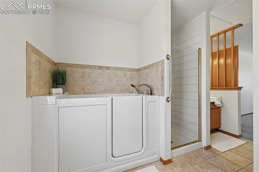 Image 13 of 42: En-suite bathroom with vanity, shower, walk-in jetted tub, toilet and walk-