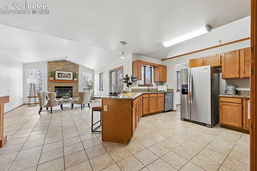 Image 15 of 42: Kitchen with breakfast bar open to family room with walk-out, tile floors