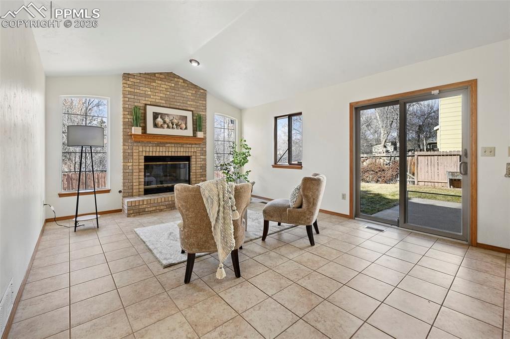 Image 20 of 42: Bright family room with brick gas fireplace, slider walk-out to concrete pa