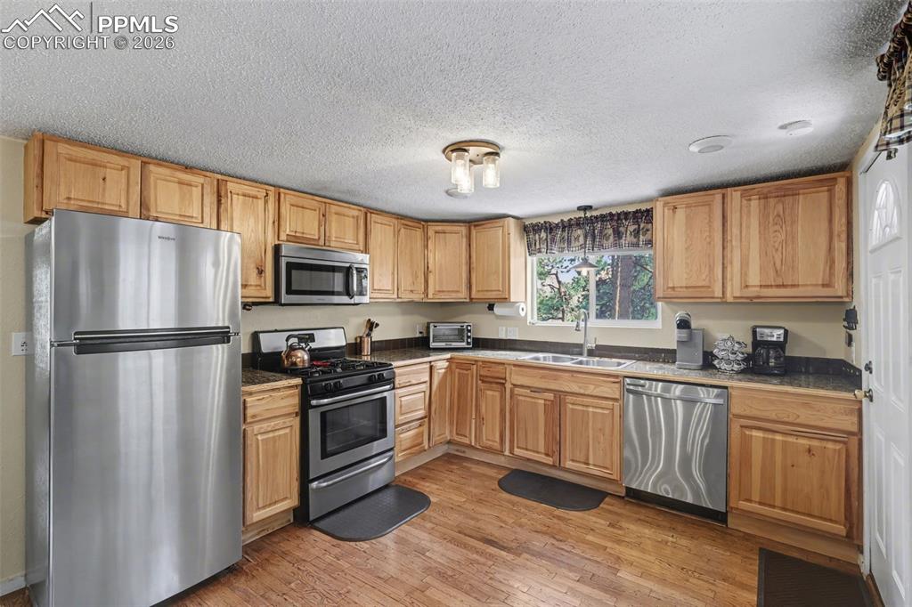 Image 10 of 33: Kitchen with stainless steel appliances and hardwood flooring
