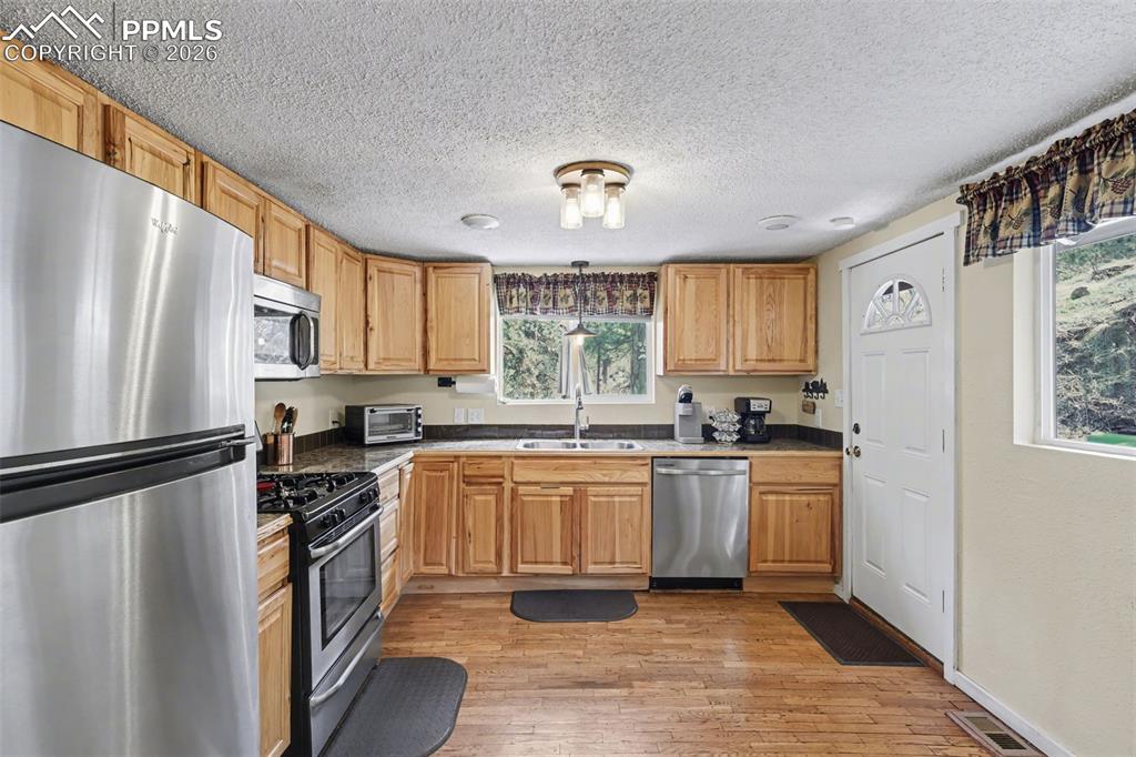 Image 11 of 33: Kitchen featuring stainless steel appliances, light wood-type flooring, dar