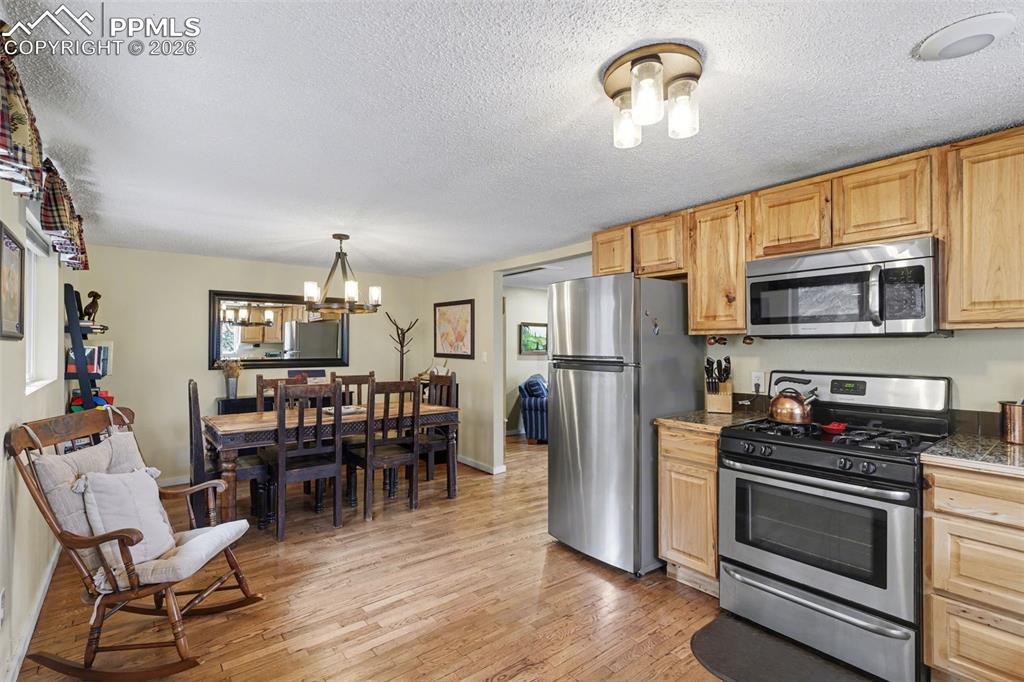 Image 12 of 33: Kitchen featuring stainless steel appliances, light wood-style flooring, ha