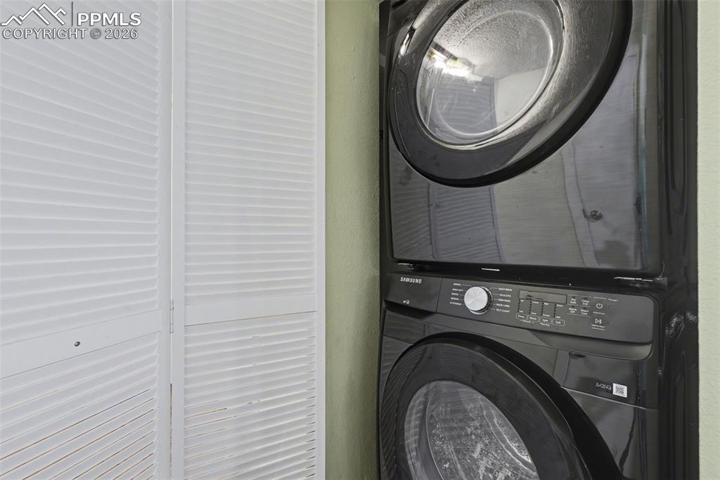 Image 19 of 33: Laundry area with stacked washer and clothes dryer