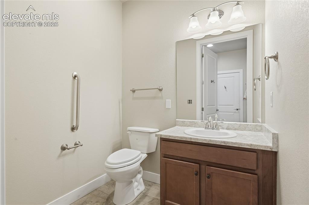 Image 13 of 28: Bathroom featuring a wood-finish vanity with an integrated sink, stone-fini