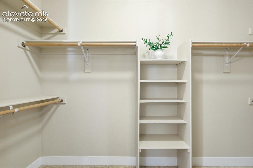 Image 19 of 28: Built-in shelving unit, wood-tone hanging rods, and white wall finishes