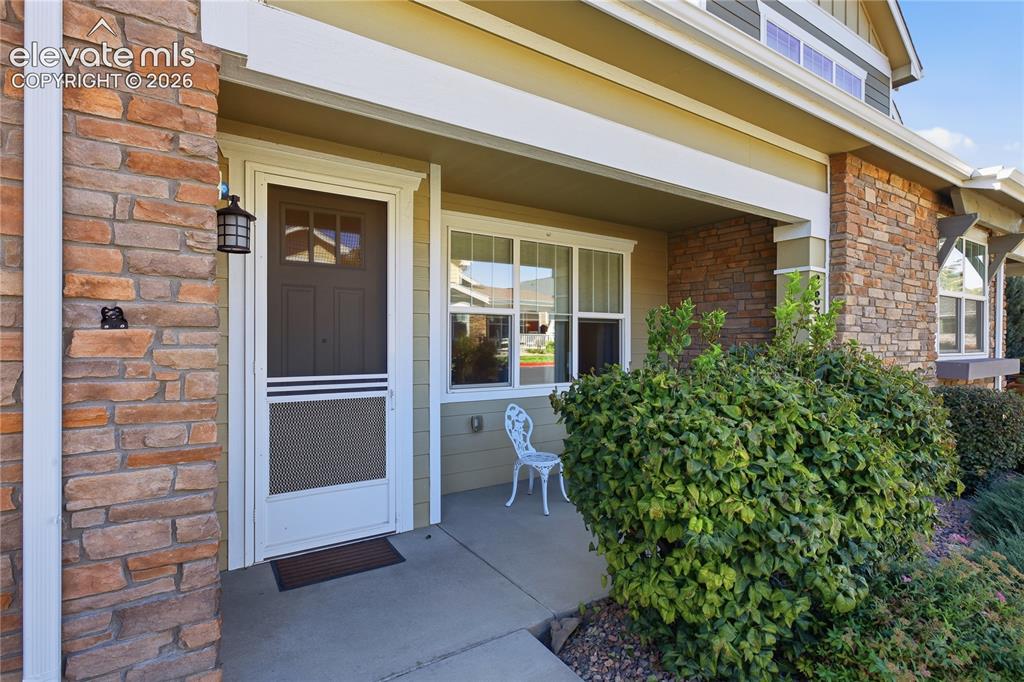 Image 2 of 28: Covered front porch with stone facade accents, decorative exterior lighting