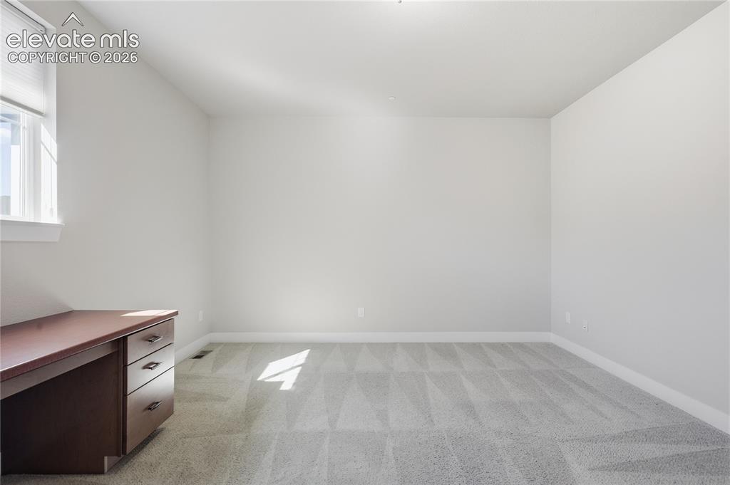Image 21 of 28: Light gray walls, patterned carpeting, white trim, and a window with blinds