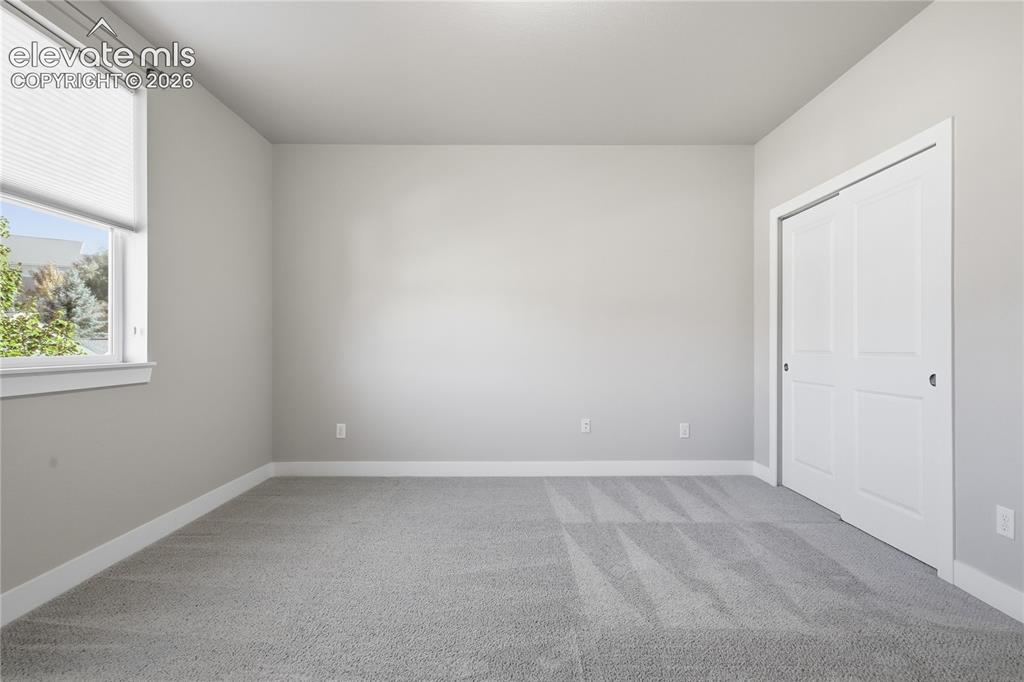 Image 26 of 28: Neutral wall tones with white trim, gray carpet, a double-pane window, and