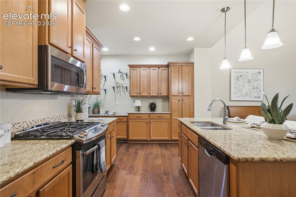 Image 9 of 28: Kitchen with wood-finish cabinetry, stainless steel appliances, granite cou