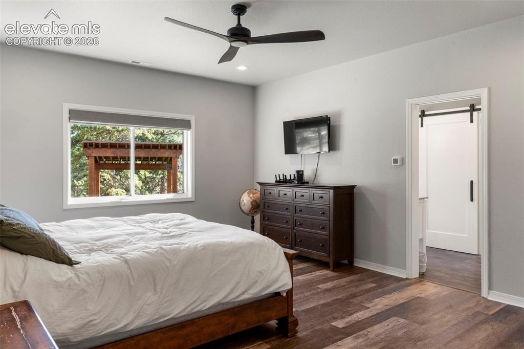 Image 17 of 46: Bedroom with dark wood finished floors, ceiling fan, and recessed lighting