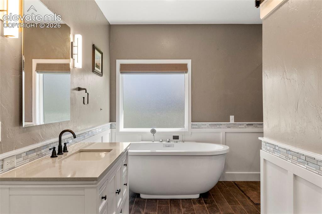 Image 19 of 46: Bathroom with vanity, a freestanding bath, a textured wall, wood finish flo