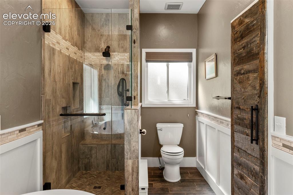 Image 20 of 46: Bathroom featuring a textured wall, a shower stall, wood tiled floors, and