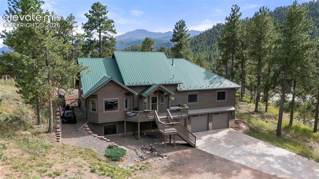 Image 40 of 46: View of front facade with stairway, a deck with mountain view, a metal roof