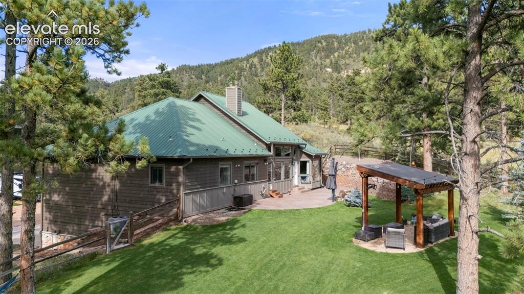 Image 43 of 46: Back of property featuring a patio area, a wooded view, a metal roof, an ou