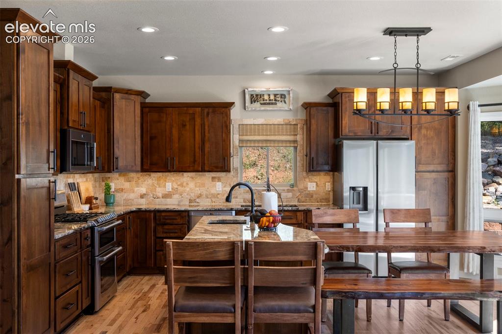 Image 7 of 46: Kitchen featuring light stone counters, stainless steel appliances, light w
