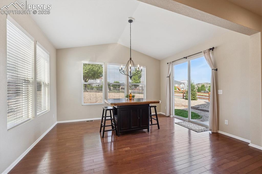 Image 12 of 36: Dining room with a chandelier, lofted ceiling, and dark wood finished floor