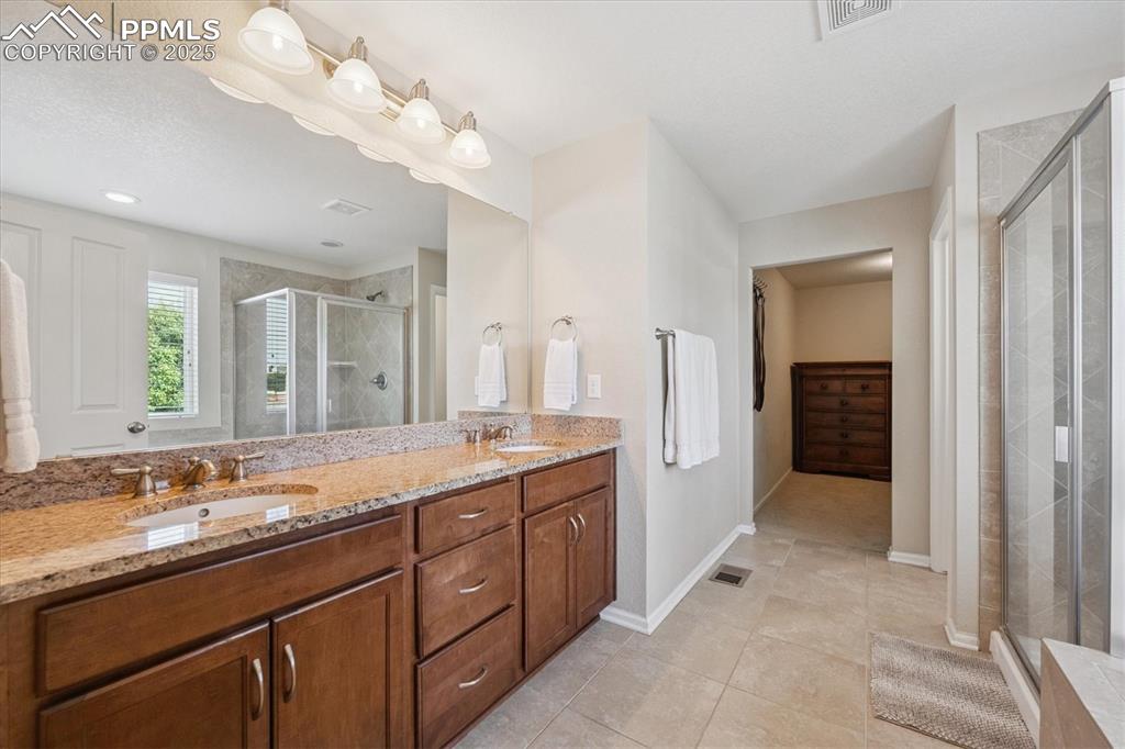 Image 18 of 36: Full bathroom with a stall shower, double vanity, and tile patterned floori