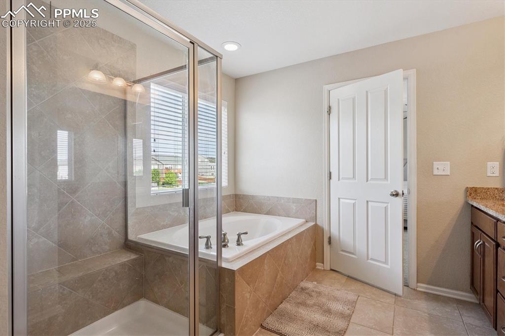 Image 19 of 36: Bathroom with vanity, a bath, a shower stall, and tile patterned floors