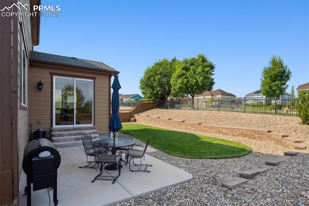 Image 28 of 36: Fenced backyard with entry steps, a patio, and area for grilling