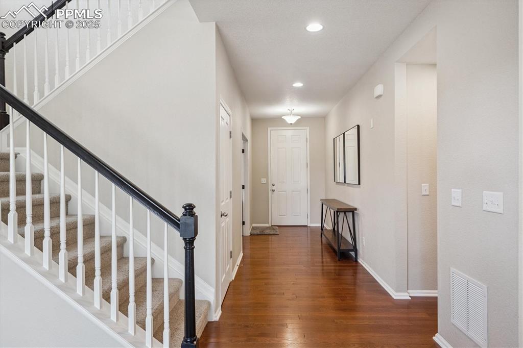 Image 3 of 36: Foyer entrance with wood finished floors, stairway, and recessed lighting