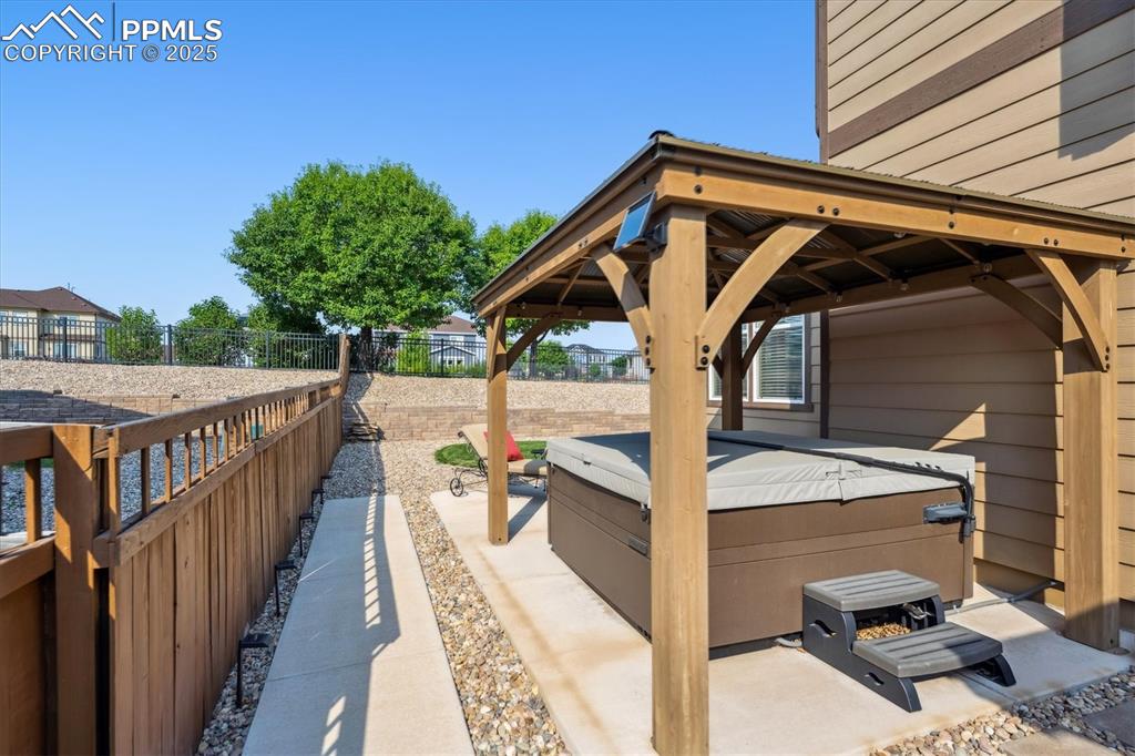 Image 32 of 36: Fenced backyard with a hot tub, a gazebo, and a patio area