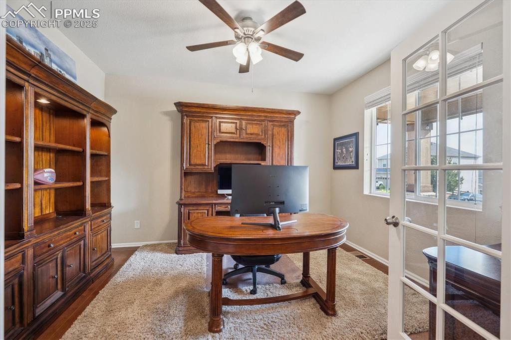 Image 4 of 36: Office space with dark wood-style flooring, a ceiling fan, and french doors