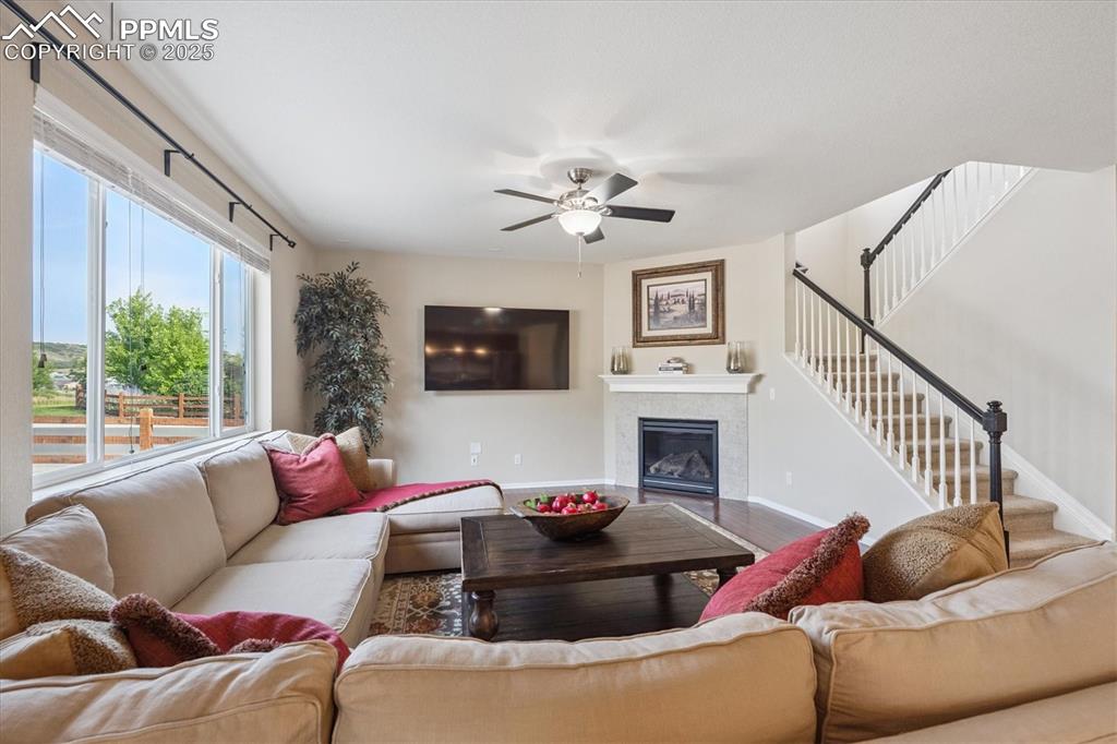 Image 6 of 36: Living area with a tile fireplace, wood finished floors, stairs, and ceilin