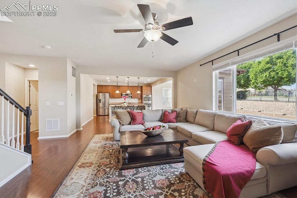 Image 8 of 36: Living room with dark wood-style flooring, recessed lighting, stairway, and